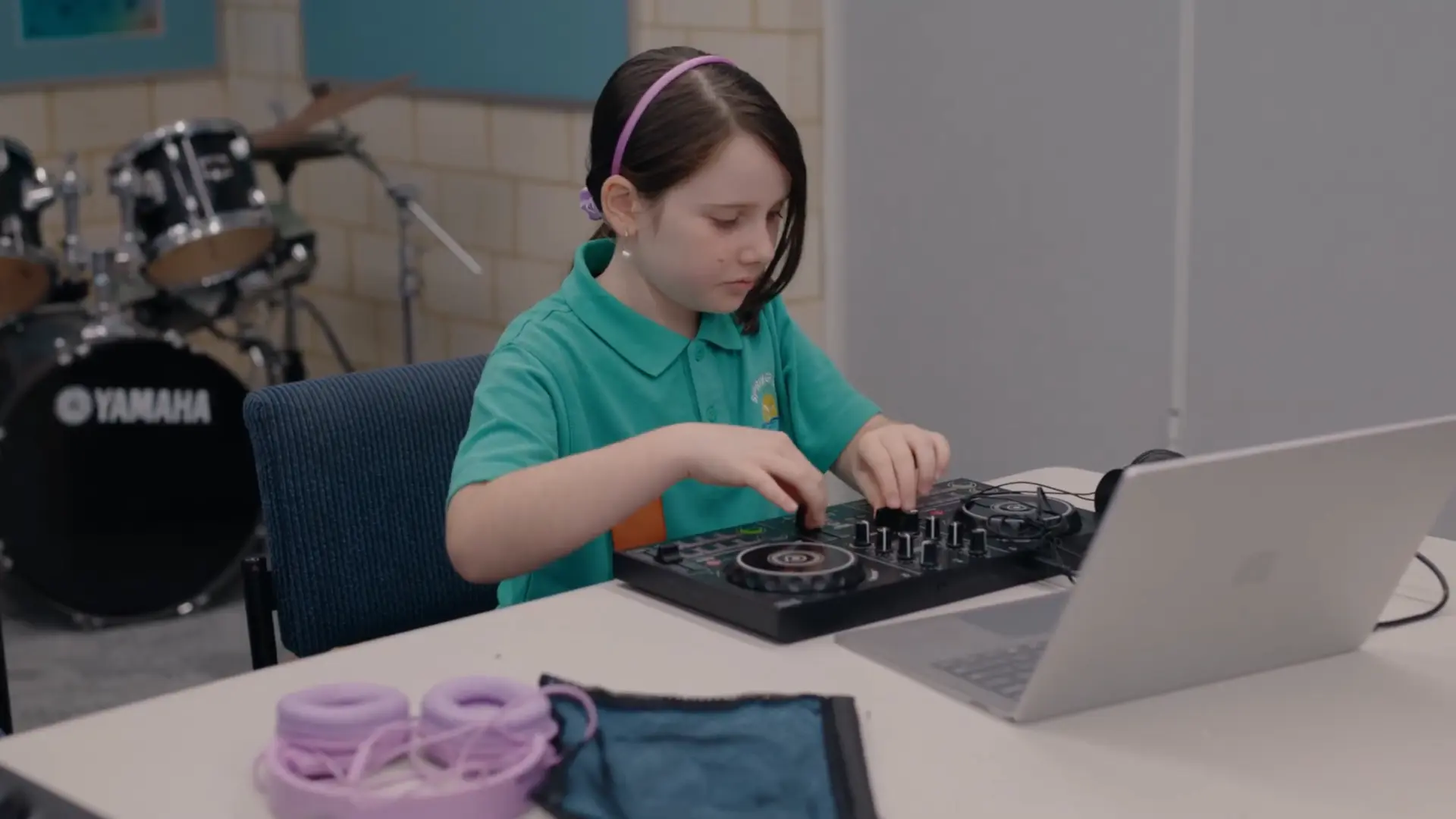 A primary school student learning to mix on a compact DJ controller